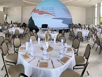 Image of a large globe with an ocean imaged projected on it, in the center of round lunch tables.